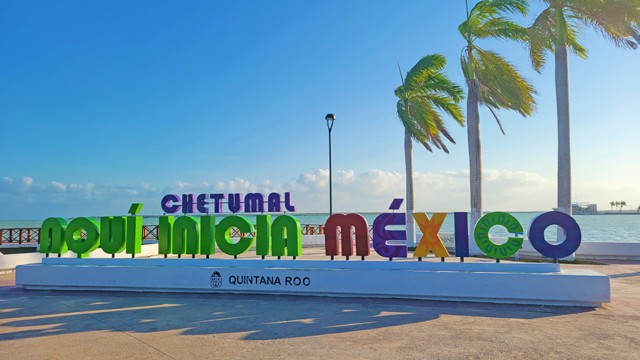 The colorful sign "Chetumal: Aquí Inicia México" (Chetumal: Here Mexico Begins) greets visitors with its vibrant letters against the backdrop of swaying palm trees and the beautiful coastline. This landmark symbolizes Chetumal's status as the southern gateway to Mexico.