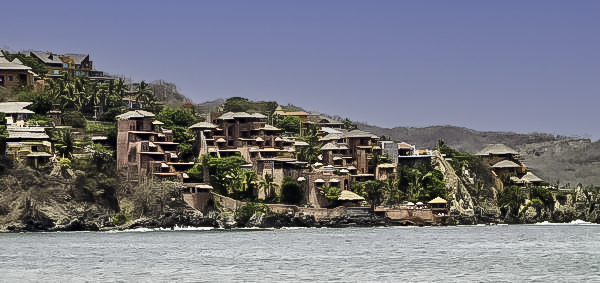 A stunning view of luxury villas perched on the cliffs overlooking the Pacific Ocean in Zihuatanejo, Guerrero, showcasing the town's unique blend of natural beauty and upscale accommodations.