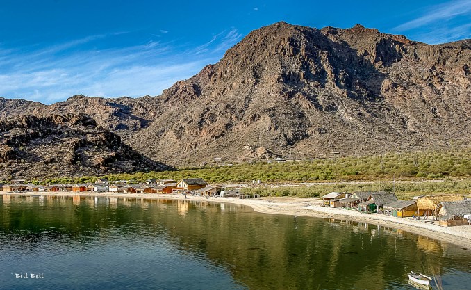 RVs and campers line the sandy shores of Bahia Conception, creating a community of adventurers enjoying the serene landscape and stunning sunsets over the bay.