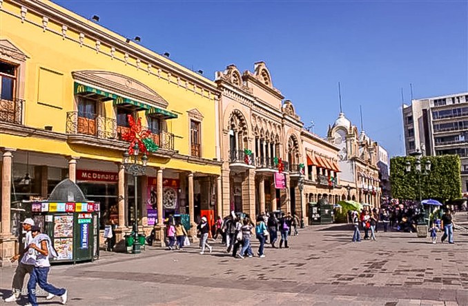  A vibrant street scene in León, Guanajuato, showcasing the blend of historic architecture and modern storefronts, including a prominent McDonald's within a charming colonial building.