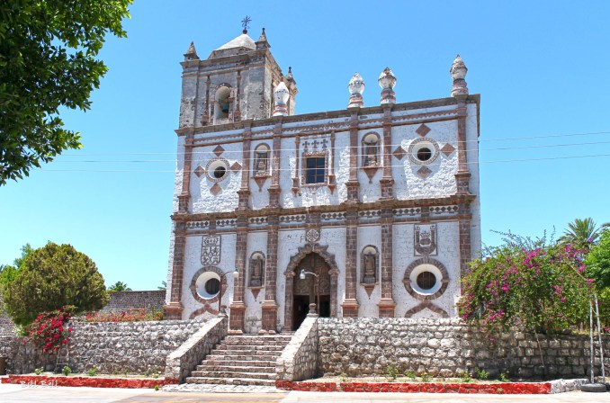 he beautiful and historic Mission of San Ignacio, Baja California Sur, stands proudly under the clear desert sky. This mission, dating back to the 18th century, is a testament to the resilience and artistry of Spanish colonial architecture, blending with the serene desert surroundings.