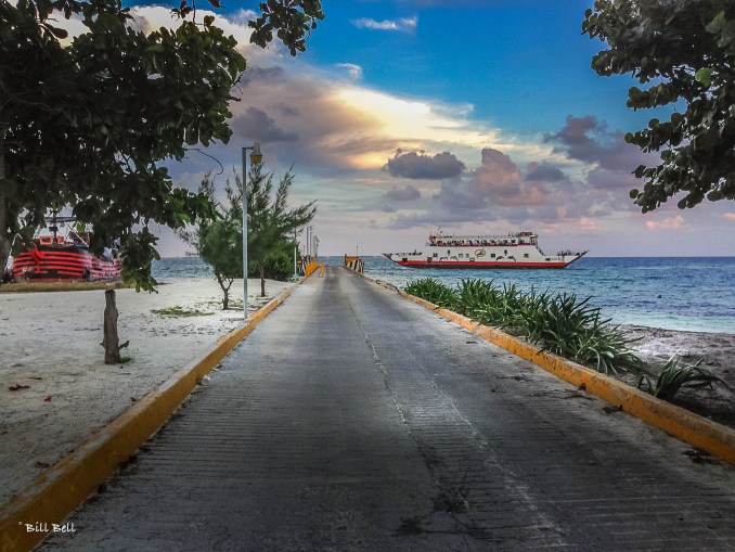 As the sun sets over Isla Mujeres, a ferry arrives at the island's dock, bringing visitors to this tranquil paradise just a short ride from Cancun.