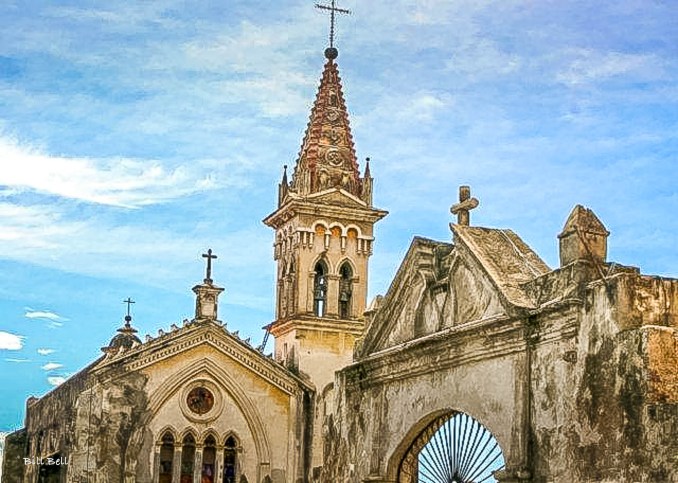 The iconic steeple of a historic church in Cuernavaca, standing tall against a backdrop of a clear blue sky, showcasing the city's blend of colonial architecture and spiritual heritage.