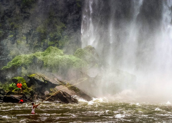 Fishing Under the Waterfall: A local fisherman skillfully casts his line near the powerful cascades of Salto de Eyipantla, showcasing the area's natural beauty and traditional practices. (Photo by Bill Bell)