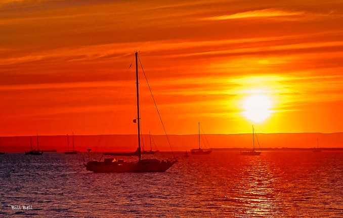  A stunning sunset over La Paz Bay, where sailboats gently float on the tranquil waters, bathed in the warm, golden hues of the setting sun.