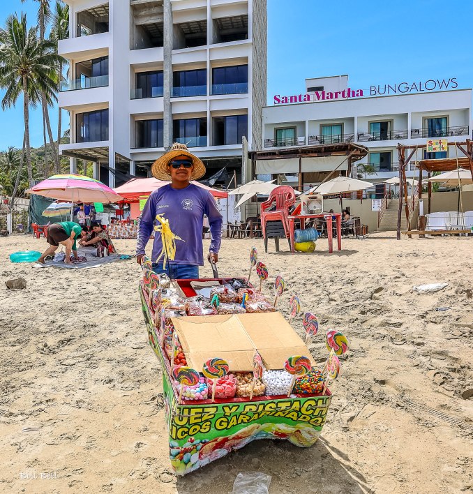 A friendly vendor offering traditional Mexican candies and sweets along the sandy shores of Los Ayala.