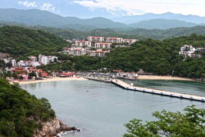 Overlooking Huatulco’s harbor, with its calm waters and vibrant greenery, set against the backdrop of distant mountains