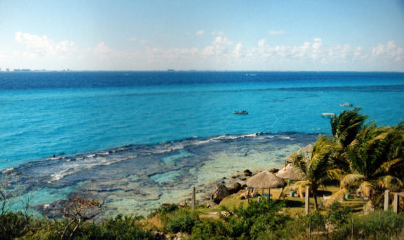 A breathtaking view of the vibrant blue waters surrounding Isla Mujeres, with the rugged coastline and distant horizon highlighting the island's natural beauty.