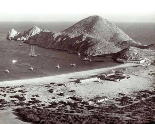 A historical view of Cabo San Lucas, showcasing its early days as a small fishing village with a picturesque harbor and minimal development.